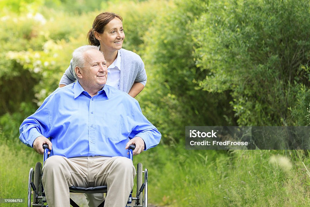 Старший человек, сидя на инвалидной коляске с лицом, осуществляющим уход - Стоковые фото Пожилой возраст роялти-фри
