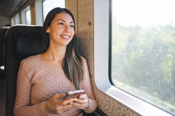 istock Brunette woman inside the train looking out the window while using her mobile phone 1700888729