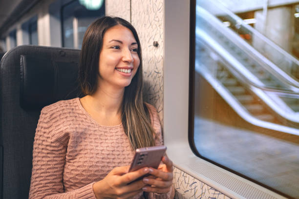 istock Brunette woman inside the train looking out the window while using her mobile phone 1700890353
