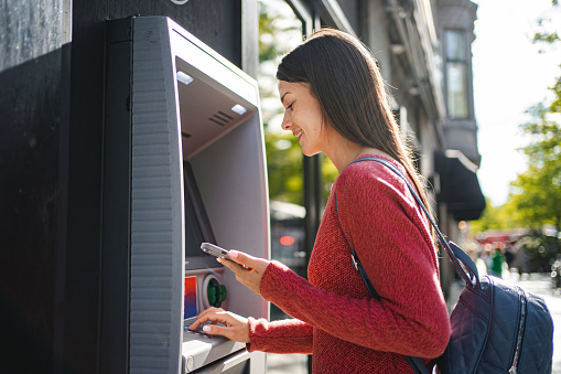 Caucasian woman withdrawing money at the outdoor ATM machine