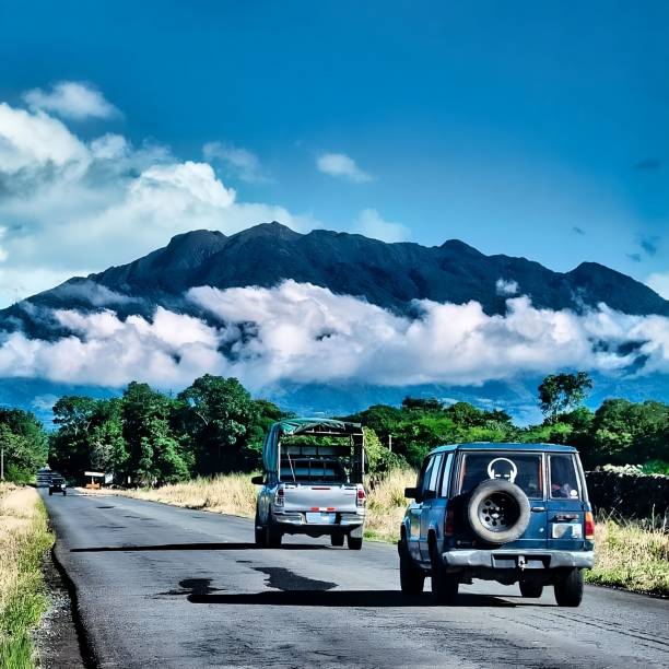 istock three vehicles driving down a road by a mountain with the clouds in the background 1700900388