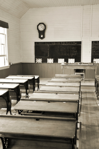 Old classroom student desks in a rural one room schoolhouse... Sepia with view to the front of the room.