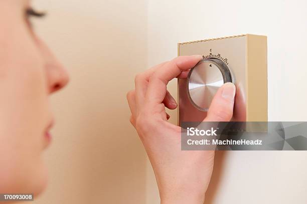 Central Heating Thermostat Control On Wall Adjusted By Woman Stock Photo - Download Image Now