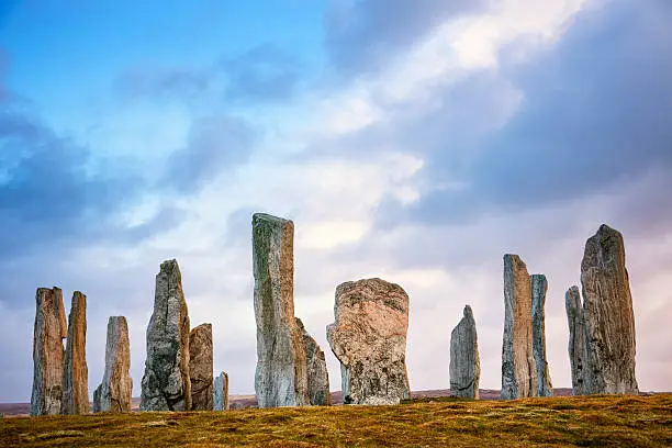 Sunset light on the ancient standing stones of Callanish (or Calanais) on Lewis in the Outer Hebrides of Scotland. Built about 5000 years ago, the deeply textured stones of Callanish are arranged in allignments of avenues and a central circle not unlike a celtic cross.