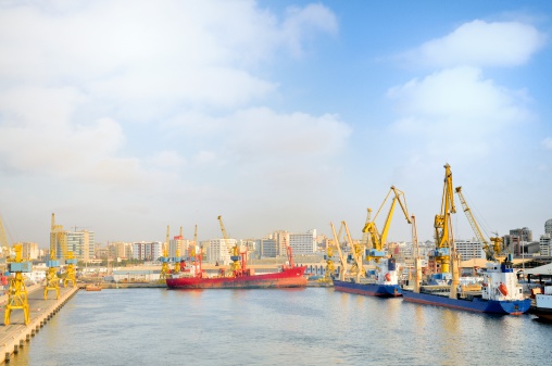 Casablanca as seen from the entrance to the port fairway with a red tanker ship docked and the cityscape in the background and other cargo ship at the piers