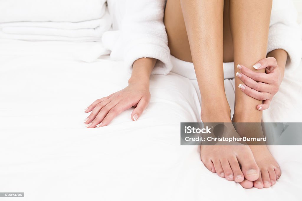 Woman wearing robe sitting on bed Close-up of barefoot  Pedicure Stock Photo