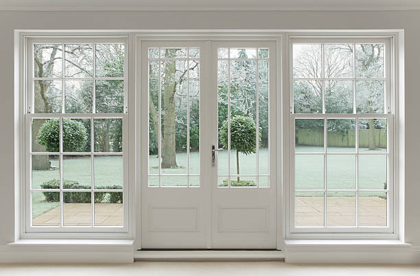 frosty view through white windows Beautifully crafted Georgian white wooden windows and patio doors with a view towards a wintery garden covered in frost.  georgian style photos stock pictures, royalty-free photos & images