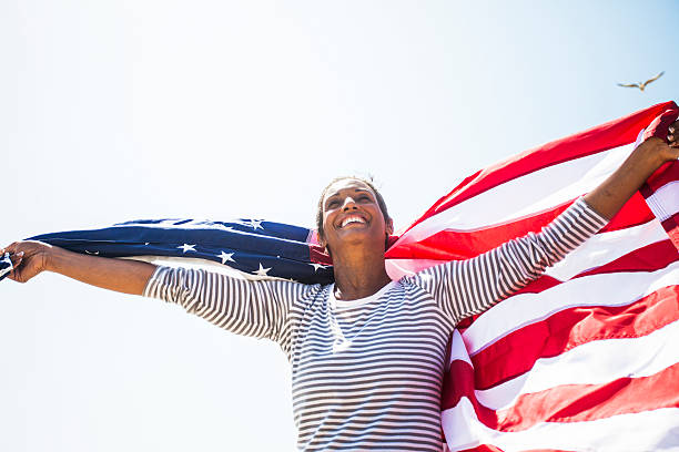 African American Senior Carrying USA Flag African American Senior carrying American flag on beach lypsela2013 stock pictures, royalty-free photos & images