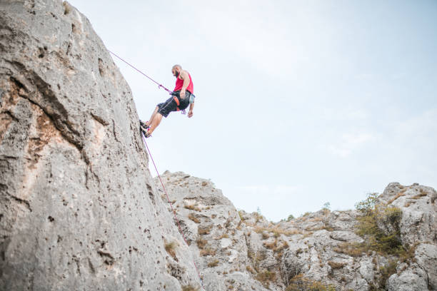istock A man overcomes extremely steep terrain by climbing a mountain and using a climbing rope 1700960413