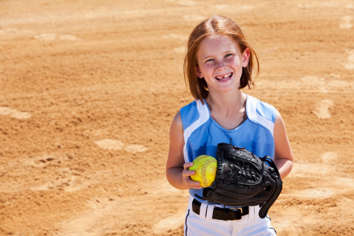 Girl (7 years) playing softball, standing on pitcher's mound.