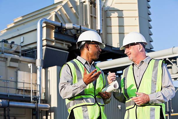 Engineers talking near power generator Multiracial male workers having discussion near power generator. (age 40s and 50s). power plant workers stock pictures, royalty-free photos & images