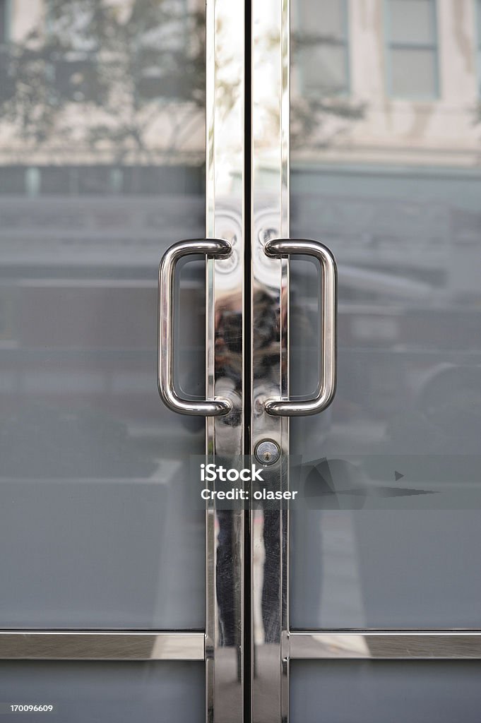 Closed. Chrome door handles of shop/office Glass doors exit/entrance with chrome door handles, glass reflecting opposite side of street Door Stock Photo