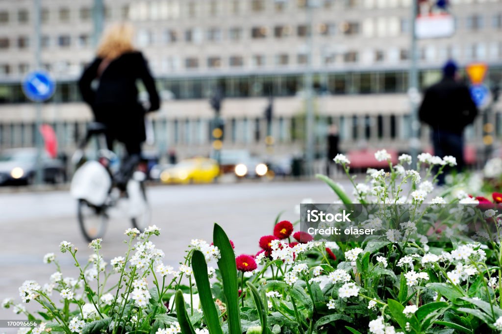 Fiori bianchi in ambiente urbano, offuscata bicyclist e pedoni - Foto stock royalty-free di Città