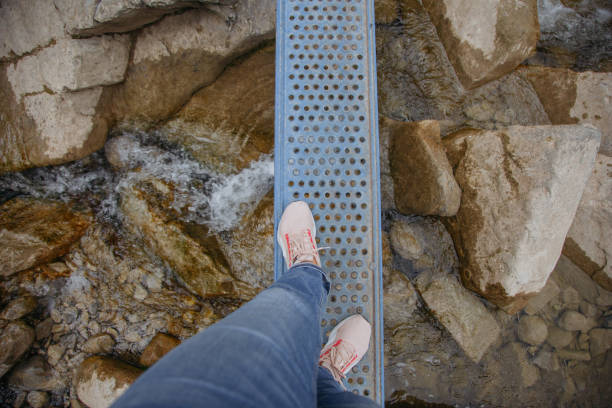 istock Man's feet on a narrow bridge over a mountain river 1700970275