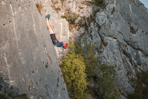 A male climber climbs a mountain using a special rope and climbing equipment