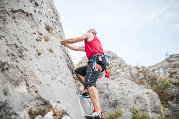 istock Strong man climbs a mountain during the day on extreme terrain 1700975635