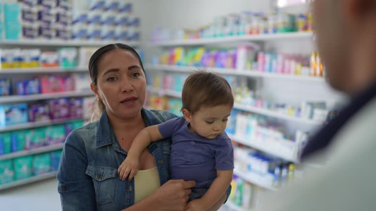 Mid adult woman with her son talking to the pharmacist at the pharmacy