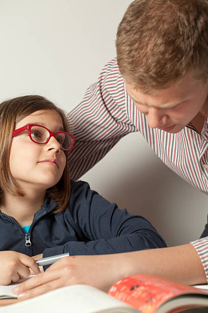 Little Girl Admiring Her Teenage Brother Solving the Homework stock photo
