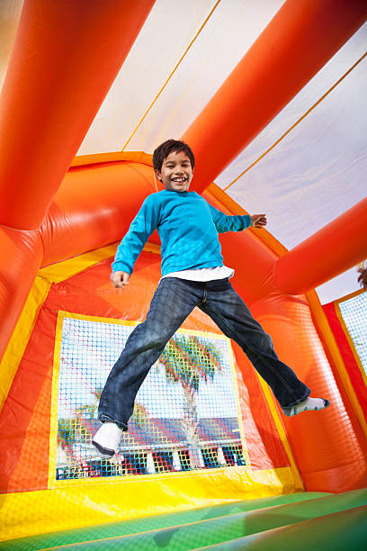 Hispanic boy (7-8 years) jumping in bouncy castle.