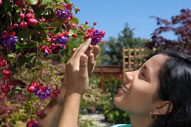 Pretty young latina woman, smelling the flowers, while shopping for garden plants