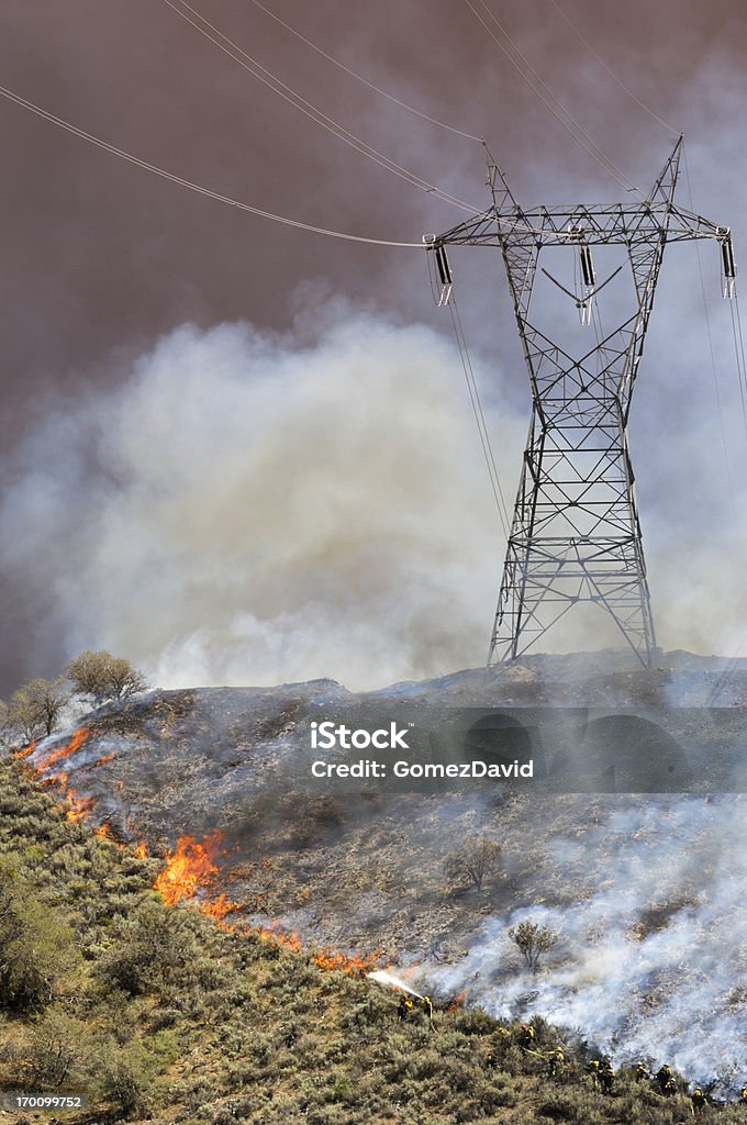 Fire Fighters Fighting Wildfire Small group of firefighters battling an out of control wildfire on a hillside, north of Los Angeles, with electrical pylon in background. Forest Fire Stock Photo