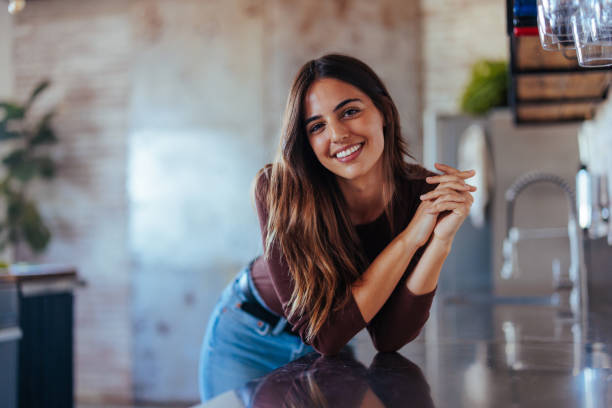 istock Woman smiling at the camera while leaning on the kitchen counter 1700997944