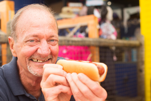 Grinning senior man eating a hot dog