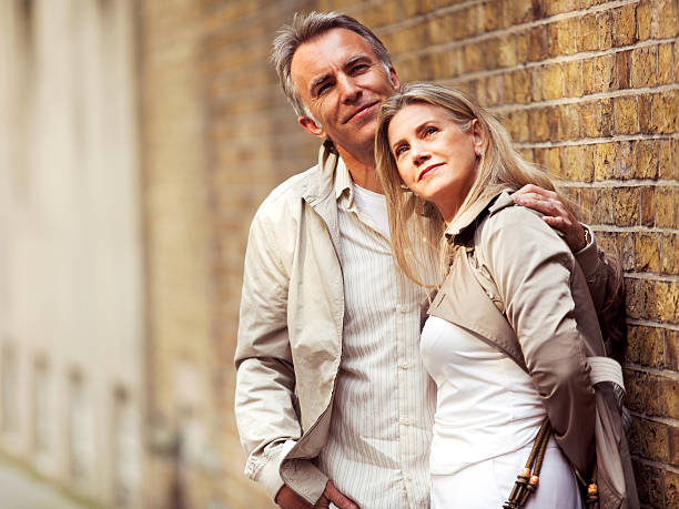 istock Smiling mature couple standing next to brick wall, looking up. 170100976