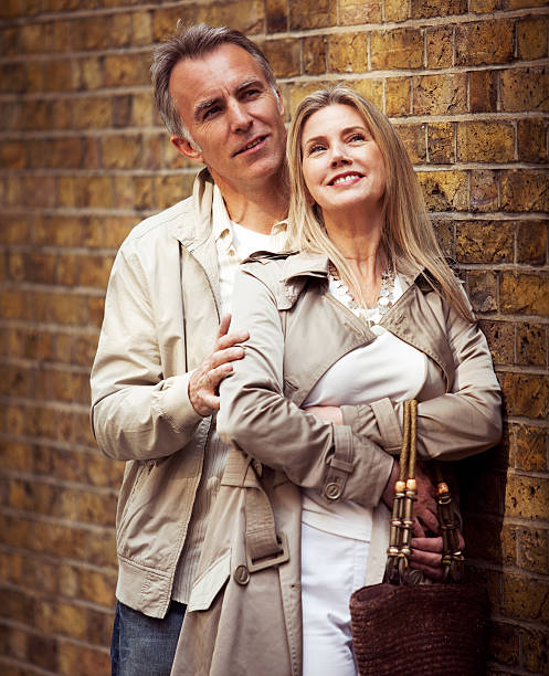 istock Smiling mature couple embracing and standing next to brick wall. 170100982