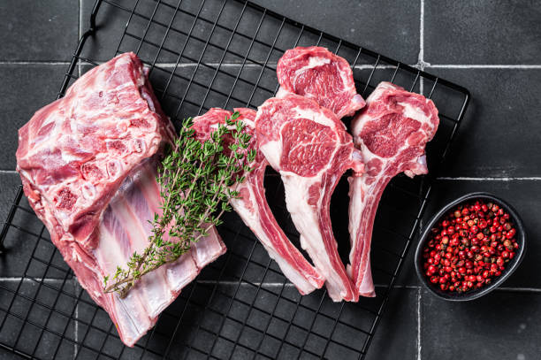 viande d’agneau crue fraîche hacher des steaks sur la table de la cuisine avec des épices et des herbes. fond noir. vue de dessus - rack of lamb chop raw meat photos et images de collection