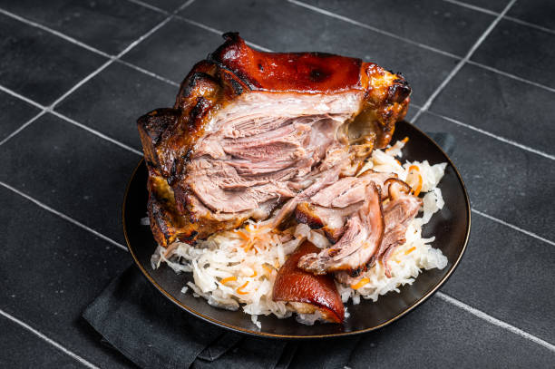 istock Roast Pork Ham Hock, knuckle with Sauerkraut on a plate. Black background. Top view 1701012599