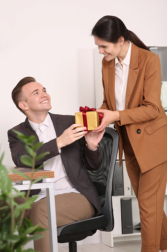Woman presenting gift to her colleague in office