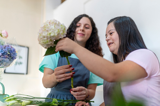 Portrait of boss and worker with disabilities making a bouquet of flowers with hydrangeas.