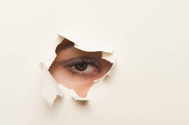 istock looking through a hole in the paper 170102515
