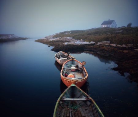 Three drifting dories on calm water, in Peggy's Cove Village, Nova Scotia at dusk.