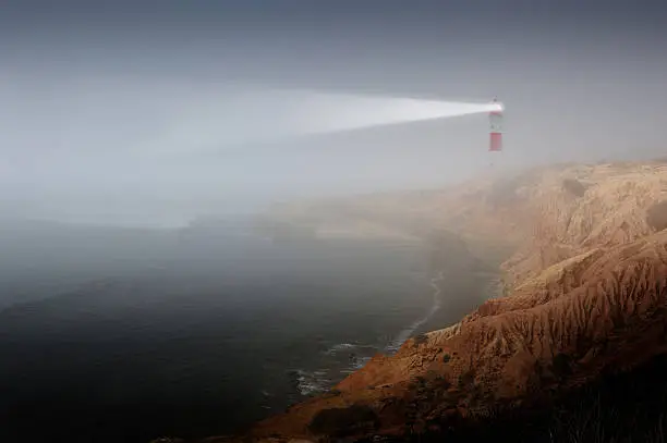 Photo of Partly sunlit rock with lighthouse