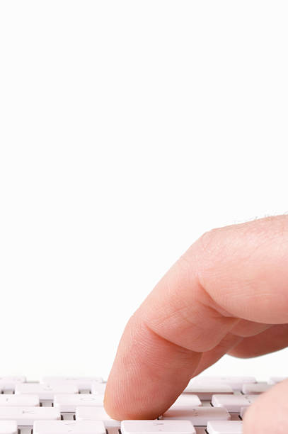 A straight ahead view of a mans fingers at a computer keyboard in front of a blank page screen, about to type. 