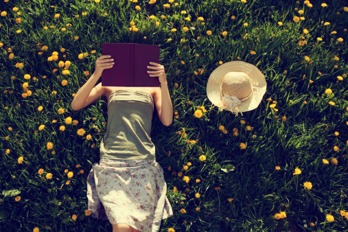 Girl lying in grass, reading a book