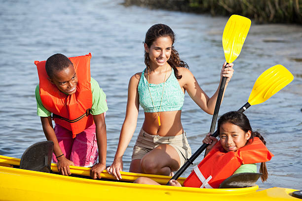 nastoletnie dziewczyny pomagają dzieciom z kajak - summer camp child teenager kayak zdjęcia i obrazy z banku zdjęć