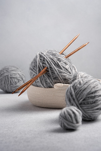 Gray balls of thread with wooden knitting needles. Needlework and leisure concept.