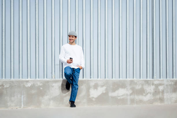 istock Relaxed young man leaning on wall with hand in pocket 1701059597