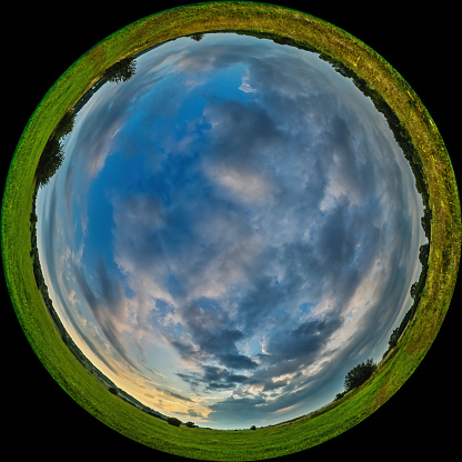 Meadow with green grass and clouds in the sky - fulldome photo format. Shot through a circular fisheye lens with a wide viewing angle of 180 degrees