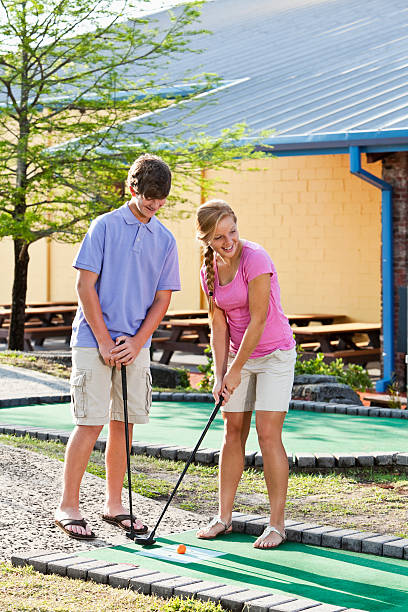 Teenage couple playing miniature golf
