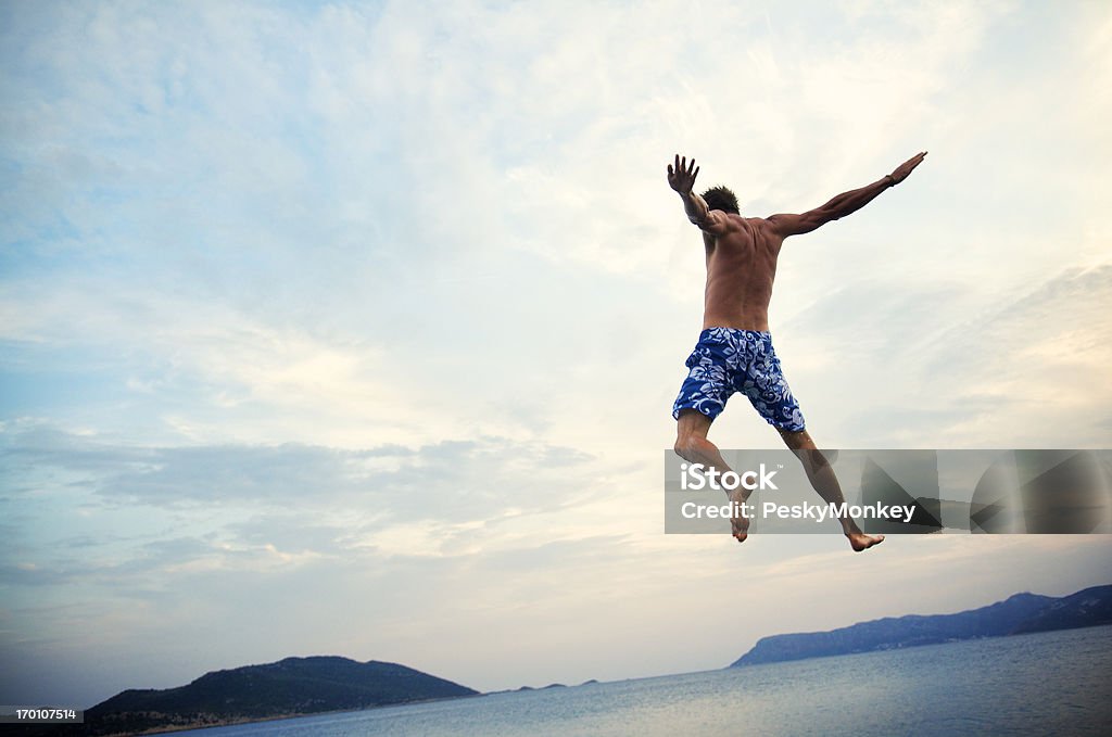 Homme en slip de bain sauts sur la mer au crépuscule - Photo de Activité de loisirs libre de droits