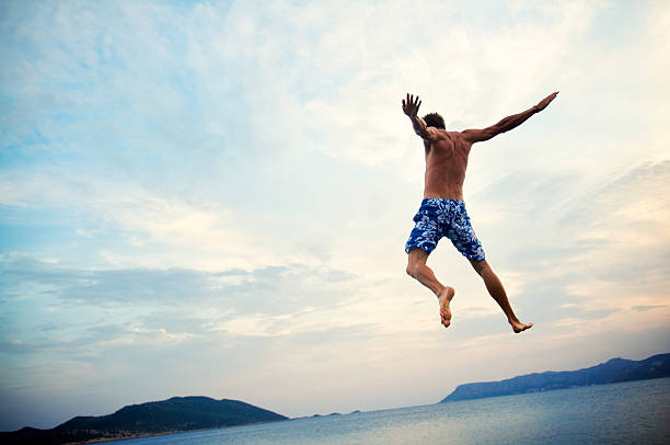 istock Man in Swimming Trunks Jumps into Sea at Dusk 170107514
