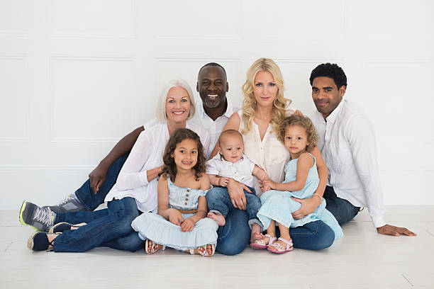 istock Multi-Ethnic Family Sitting Together Against White Wall 170107575