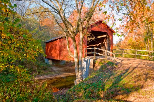 red covered bridge across stream with early autumn color, in Missouri