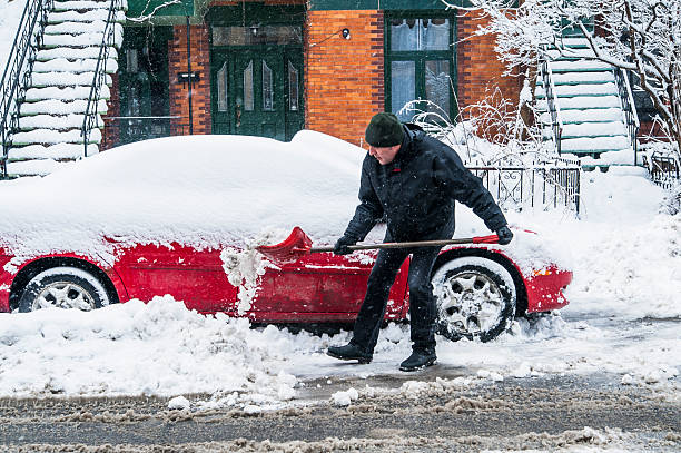 istock Man shoveling around his car on a snowing day. 170108252