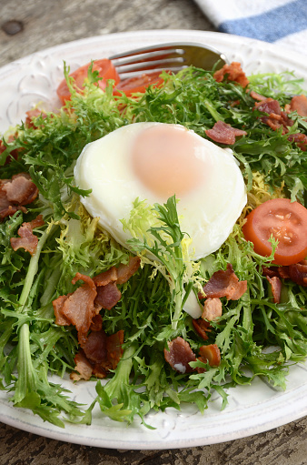 A classic French bistro salad of frisee (curly endive or chicory) topped with sauteed bacon and a poached egg.