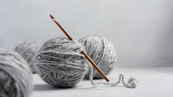 Wooden crochet hook and balls of gray yarn for crocheting and handcraft